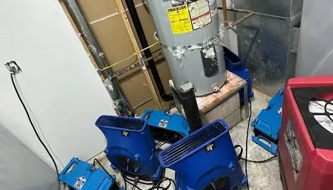 Air movers and a dehumidifier drying a water heater closet