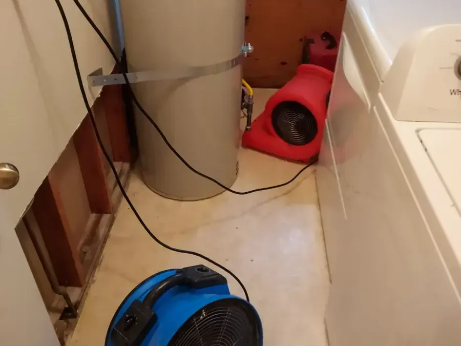Air movers beside a washing machine and opened laundry wall