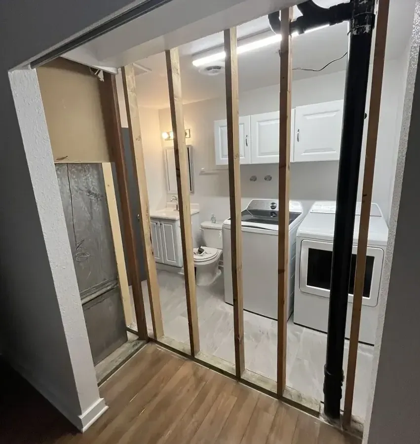 Exposed wall studs between a hallway and a laundry room