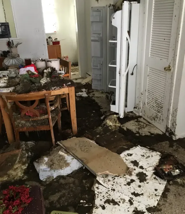 Flood debris and damaged flooring in a residential dining area