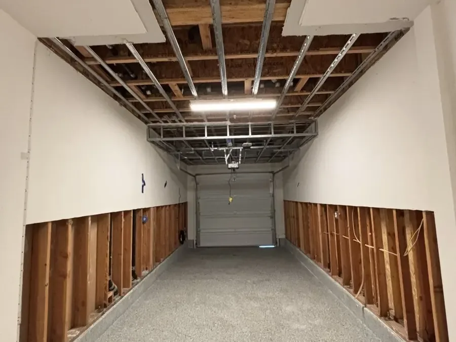 Garage with lower wallboard and ceiling panels removed for water damage work