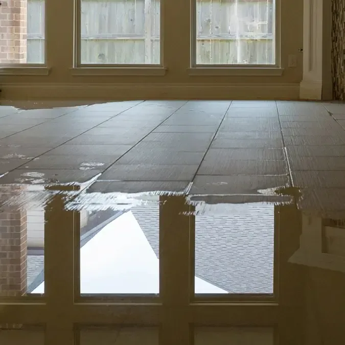 Standing water covers tiles across an empty interior floor
