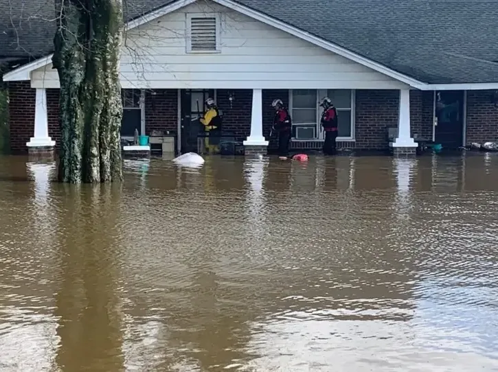 Brown floodwater surrounding the entrance of a brick house